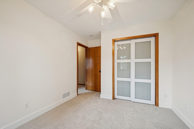 unfurnished bedroom featuring carpet flooring, a ceiling fan, baseboards, and visible vents