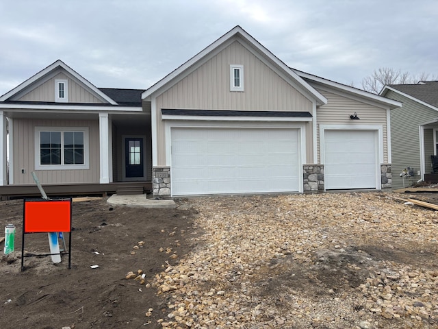 view of front of property featuring stone siding, an attached garage, driveway, and board and batten siding