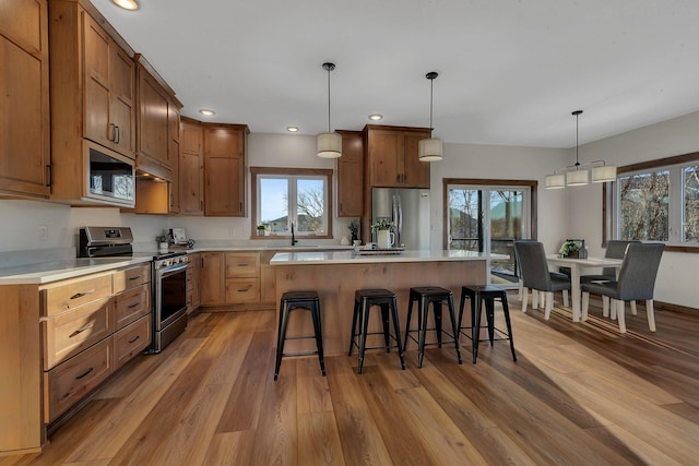 kitchen featuring a breakfast bar area, a center island, light wood-type flooring, pendant lighting, and stainless steel appliances