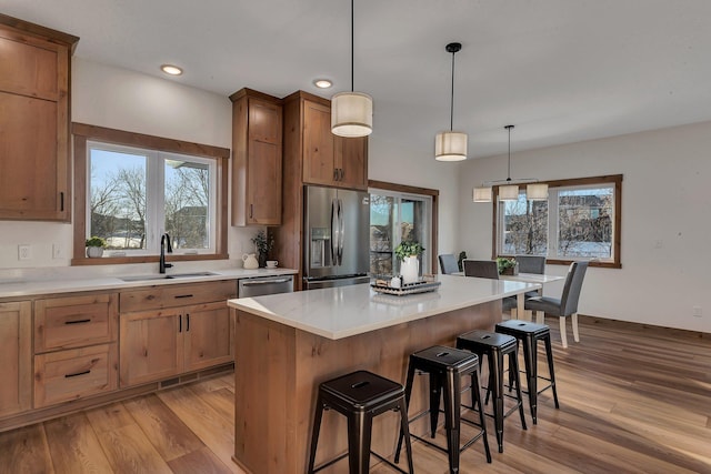 kitchen featuring decorative light fixtures, sink, a kitchen bar, a center island, and stainless steel appliances