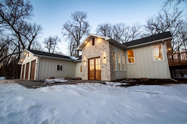 snow covered property with a garage and a deck