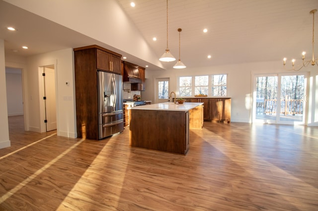 kitchen featuring pendant lighting, sink, a wealth of natural light, a center island with sink, and stainless steel fridge with ice dispenser