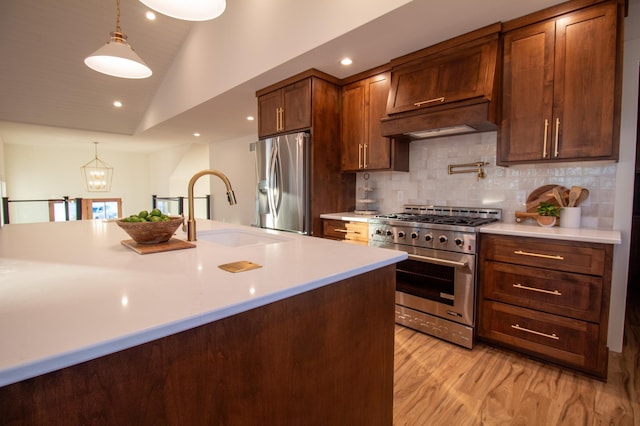 kitchen with hanging light fixtures, premium range hood, appliances with stainless steel finishes, and sink