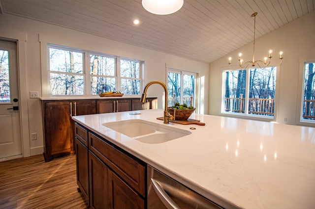 kitchen featuring lofted ceiling, sink, a notable chandelier, pendant lighting, and light stone countertops