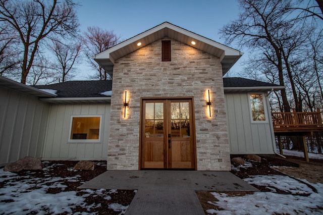 snow covered property entrance with french doors and a wooden deck