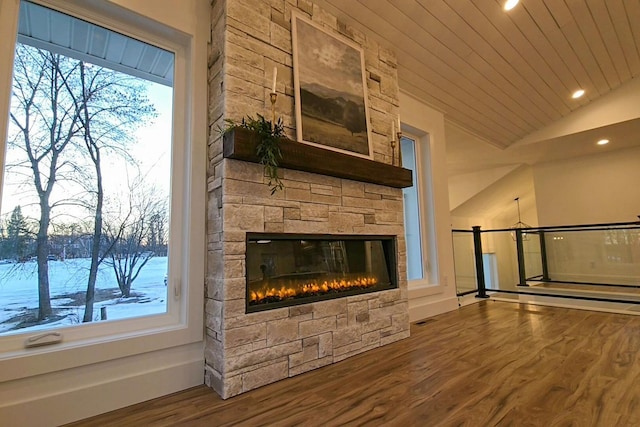 unfurnished living room featuring vaulted ceiling, a stone fireplace, wood-type flooring, and wooden ceiling