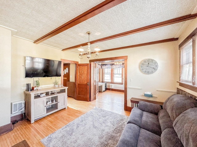 living room with an inviting chandelier, beam ceiling, light hardwood / wood-style floors, and a textured ceiling