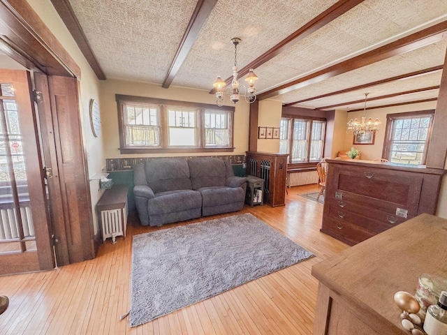 living room with radiator, beam ceiling, light hardwood / wood-style floors, and a chandelier