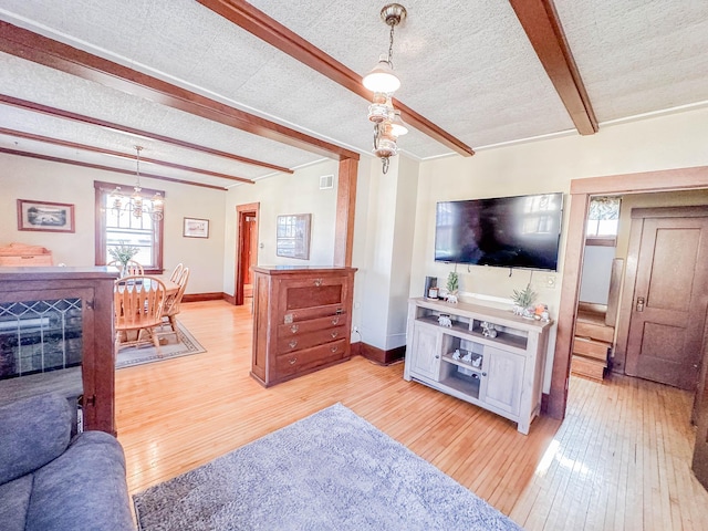 living room with a chandelier, a textured ceiling, beam ceiling, and light hardwood / wood-style floors