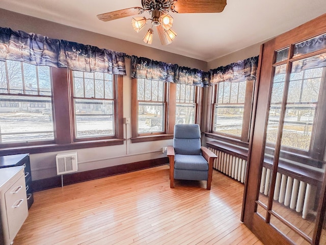 unfurnished sunroom with ceiling fan and radiator heating unit