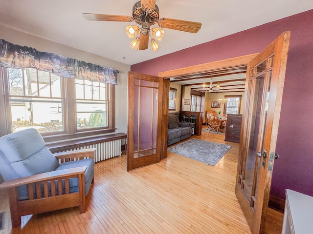 sitting room with beamed ceiling, ceiling fan, radiator heating unit, and light hardwood / wood-style flooring