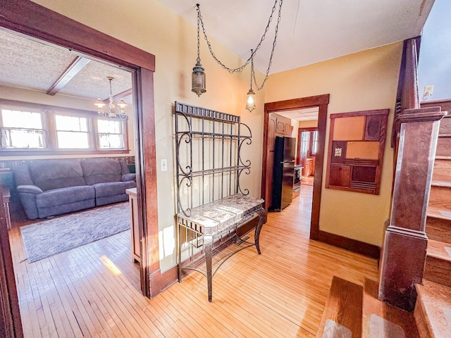 hall with an inviting chandelier, hardwood / wood-style flooring, and beam ceiling