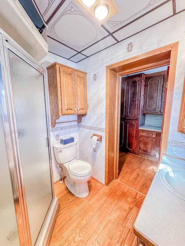 bathroom featuring tile walls, hardwood / wood-style flooring, vanity, an enclosed shower, and toilet