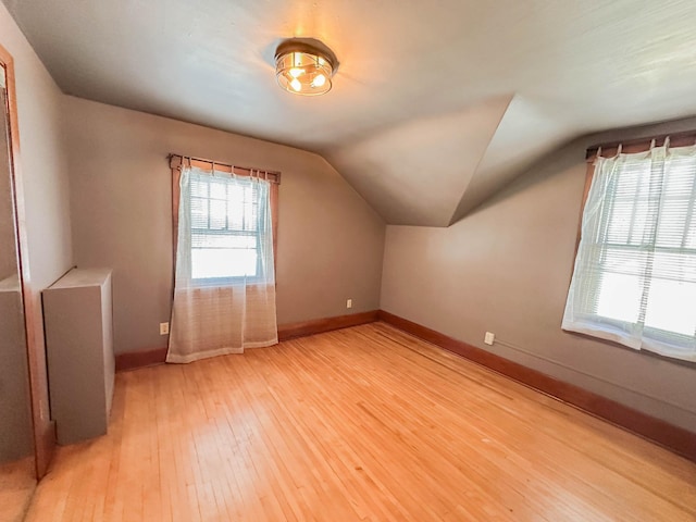 additional living space featuring lofted ceiling and light hardwood / wood-style floors