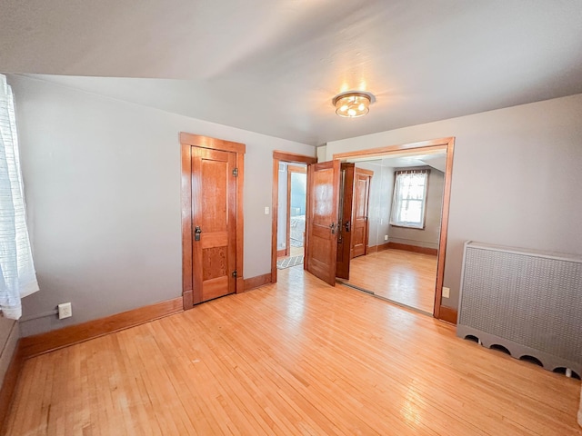 unfurnished bedroom featuring radiator heating unit, light hardwood / wood-style floors, and a closet