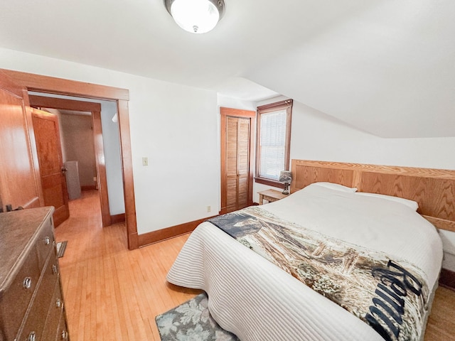 bedroom featuring a closet, lofted ceiling, and light hardwood / wood-style flooring