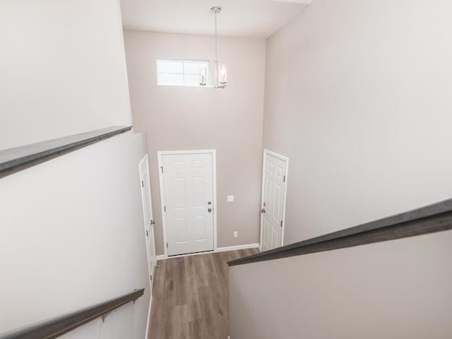 stairway with hardwood / wood-style flooring, a towering ceiling, and a notable chandelier