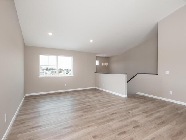 empty room featuring an inviting chandelier, light hardwood / wood-style flooring, and a healthy amount of sunlight