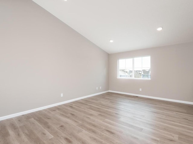 spare room with lofted ceiling and light hardwood / wood-style floors