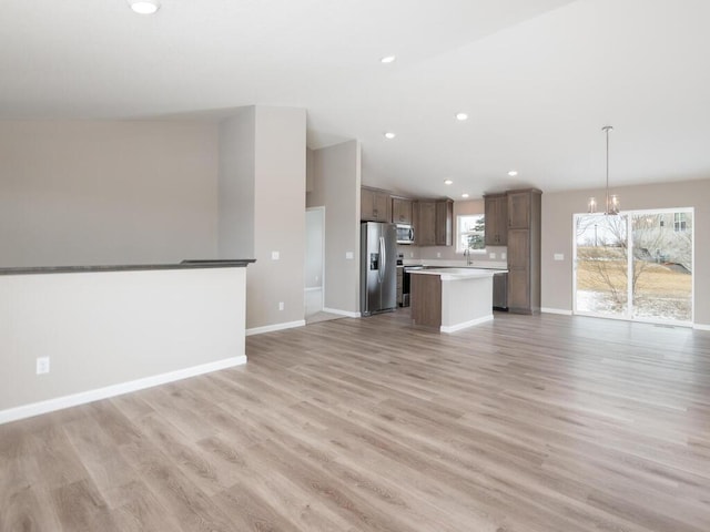 unfurnished living room with vaulted ceiling, a notable chandelier, and light hardwood / wood-style floors