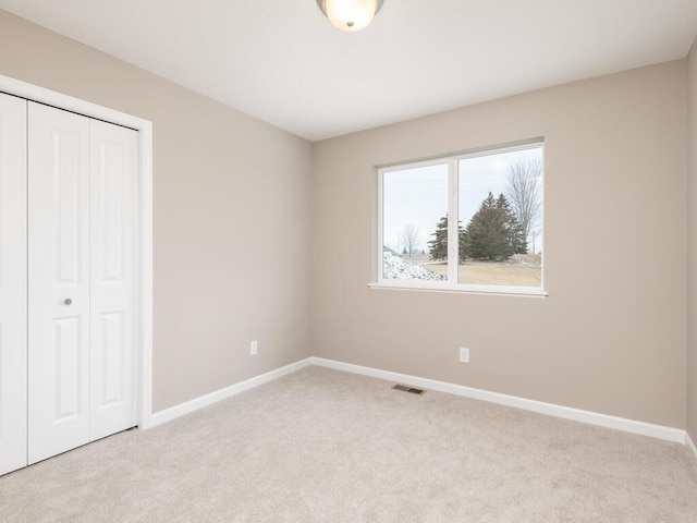 unfurnished bedroom featuring light carpet and a closet