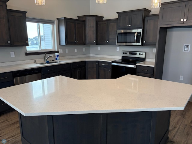 kitchen featuring appliances with stainless steel finishes, dark hardwood / wood-style flooring, a center island, and sink