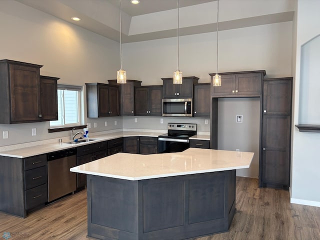 kitchen featuring hanging light fixtures, a center island, appliances with stainless steel finishes, and sink