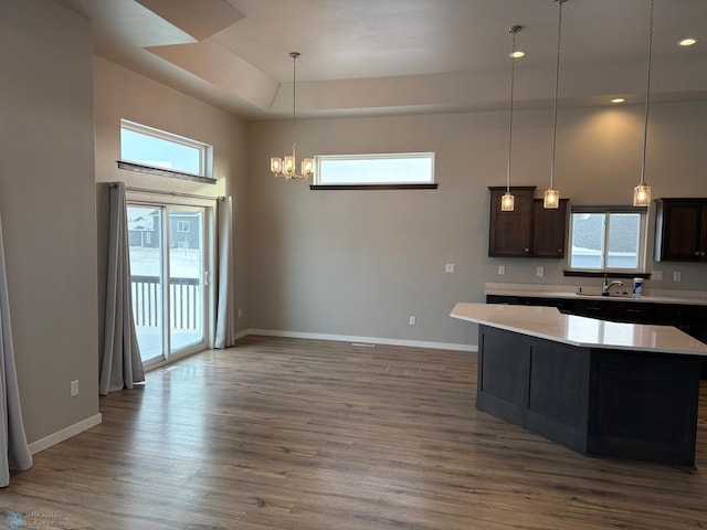 kitchen with dark brown cabinets, a center island, dark hardwood / wood-style floors, and decorative light fixtures