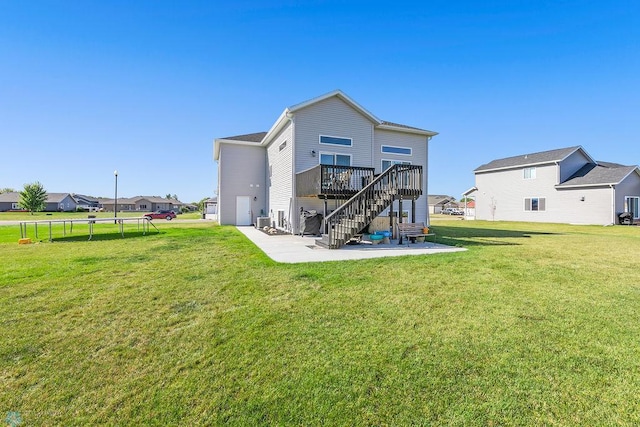 back of house with a wooden deck, a yard, a trampoline, and a patio area