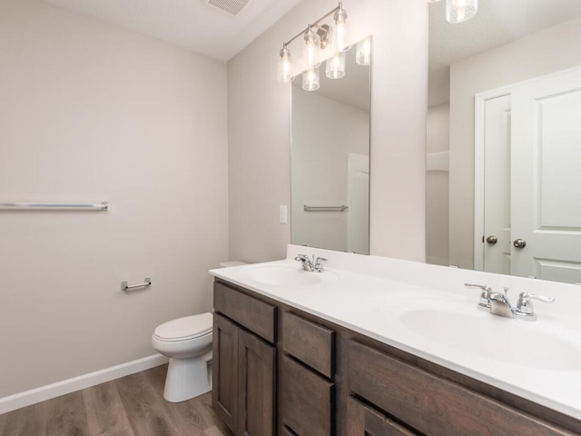 bathroom featuring wood-type flooring, toilet, and vanity