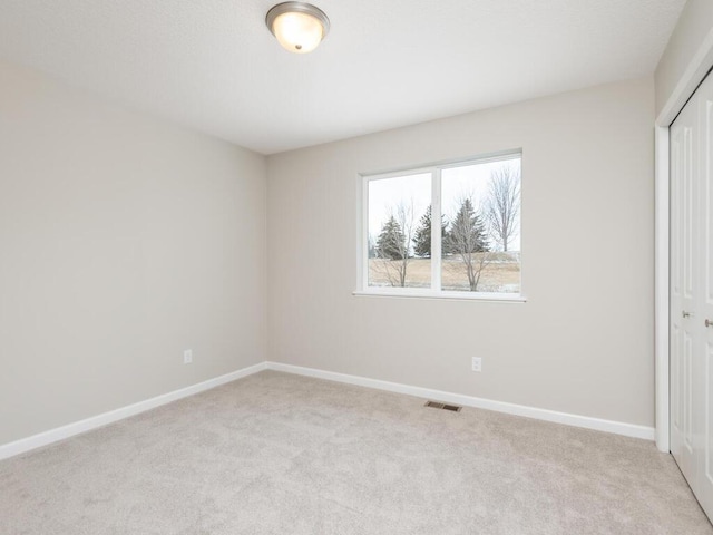 unfurnished bedroom with light colored carpet and a closet