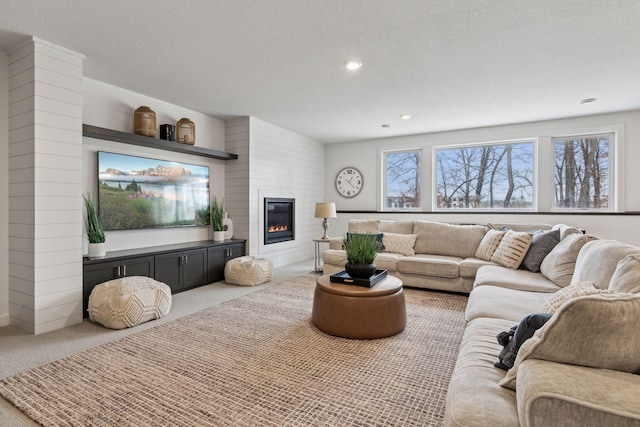 carpeted living room featuring a textured ceiling and a fireplace