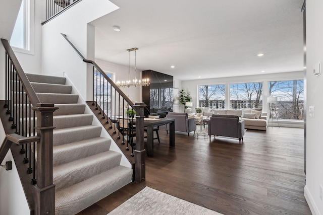 staircase with wood-type flooring and an inviting chandelier