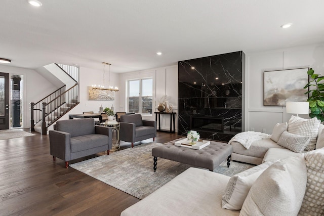 living room with an inviting chandelier, a premium fireplace, and dark hardwood / wood-style floors