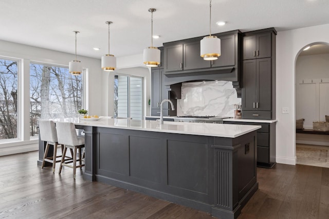 kitchen with pendant lighting, decorative backsplash, dark wood-type flooring, and a spacious island