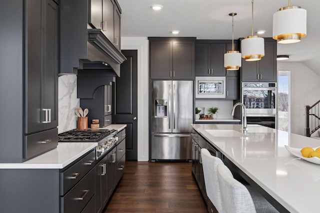 kitchen with appliances with stainless steel finishes, pendant lighting, tasteful backsplash, sink, and dark hardwood / wood-style flooring