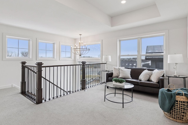 living room featuring carpet floors, a raised ceiling, and a chandelier