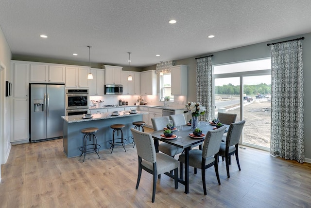 dining space featuring sink, light hardwood / wood-style flooring, and a textured ceiling