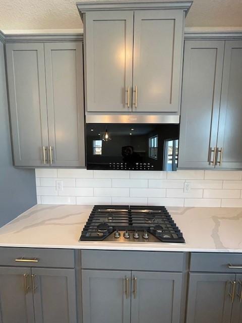 kitchen featuring decorative backsplash, gray cabinets, and stainless steel gas stovetop