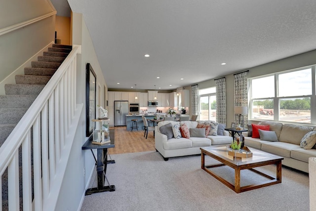 living room featuring light wood-style flooring, stairs, and recessed lighting