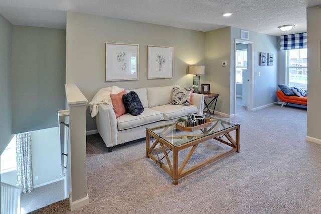 carpeted living room with a textured ceiling and baseboards