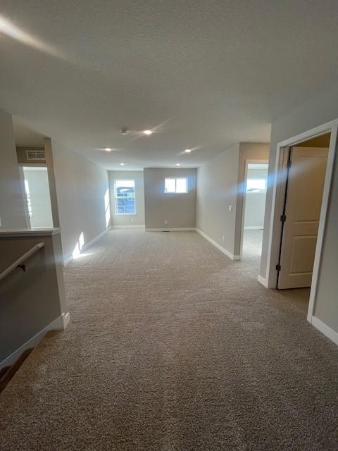 carpeted empty room featuring a textured ceiling and baseboards