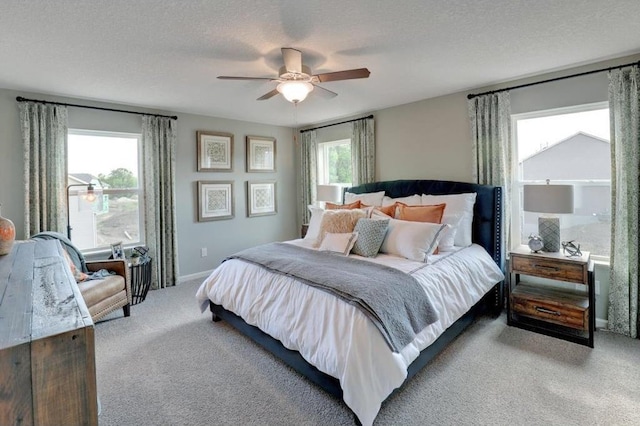 bedroom with a ceiling fan, light carpet, a textured ceiling, and baseboards