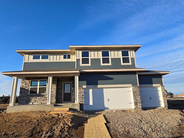 view of front of home with covered porch, stone siding, board and batten siding, and an attached garage