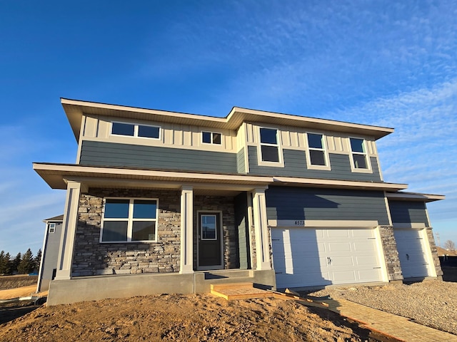 view of front of house featuring board and batten siding, stone siding, a porch, and an attached garage