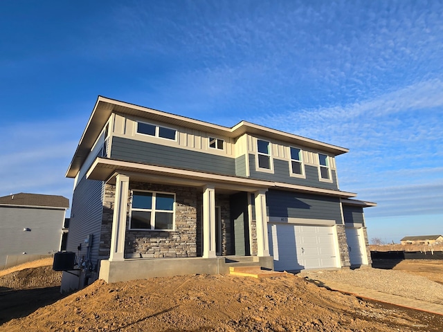 view of front of home with board and batten siding, stone siding, a porch, and a garage