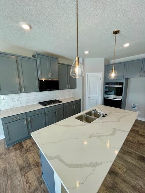 kitchen featuring hanging light fixtures, an island with sink, dark wood-type flooring, and sink