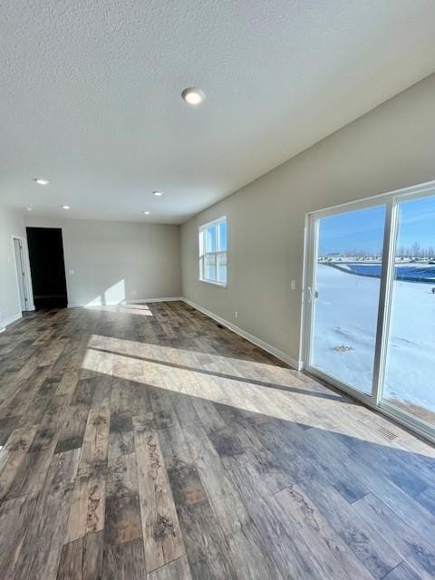 unfurnished living room with hardwood / wood-style floors, a textured ceiling, and a water view