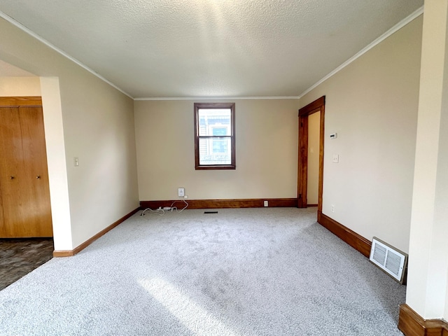 carpeted spare room featuring ornamental molding and a textured ceiling