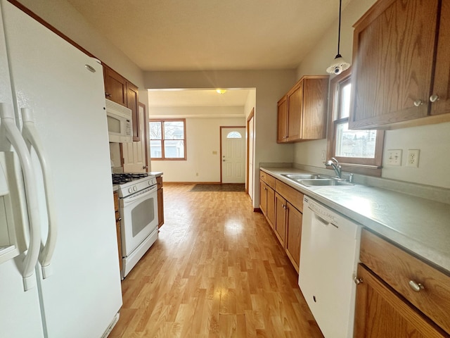 kitchen featuring pendant lighting, sink, white appliances, and light hardwood / wood-style floors